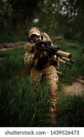 Portrait airsoft soldier with a rifle playing strikeball in outdoor in grass