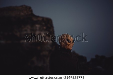 Portrait of alien head in a dark outdoors nature background. Concept of aliens among us. Extraterrestrial life. Creepy horror concept image. Life on earth and another planet discover science