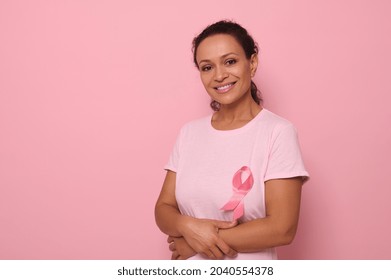 Portrait of an altruist, smiling mixed race woman in a pink T-shirt with a pink satin ribbon, symbol of International Breast Cancer Day. Educational program for the fight against cancer. 1 October