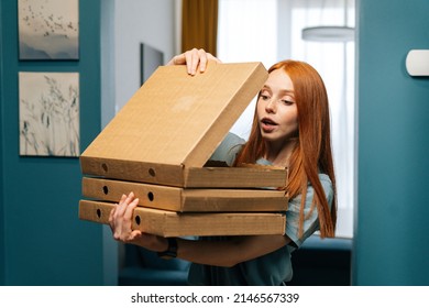 Portrait of amazed excited young woman open box of hot pizza standing at doorway to apartment, looking inside. Hunger female customer received online order from courier with prepared meal for lunch - Shutterstock ID 2146567339