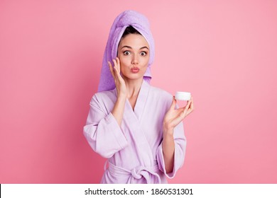 Portrait of amazed funny girlish cheery housewife wearing towel turban on hair applying night cream pout lips isolated on pink color background