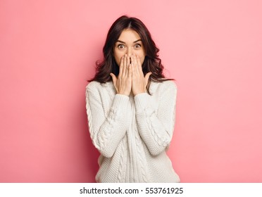 Portrait of amazed young woman over pink background