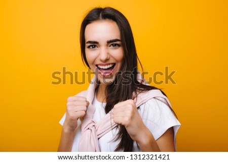 Portrait of a amazing caucasian woman showing that she is ready to win , ready to fight looking into camera laughing in front of yellow background.