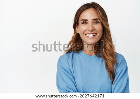 Portrait of ambitious and confident adult 30s woman, cross arms and smiling happy at camera, looking forward, standing against white background