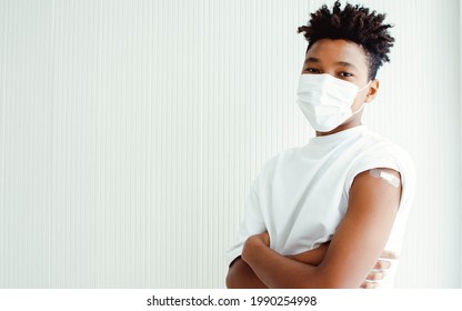 Portrait American African Teen Young Man Smart Posing, Crossing Arms With Confidence, Getting Vaccination To Prevent Covid19 Virus With Plastic Bandage On His Shoulder, Copy Space And White Background