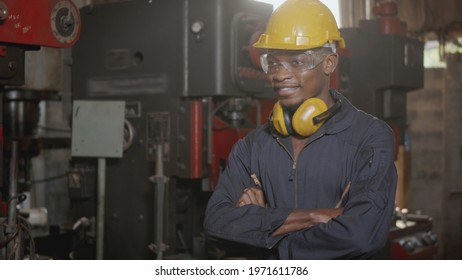 Portrait American Industrial Black Young Worker Man Smiling With Yellow Helmet In Front Of Machine, Happy Engineer Standing Arms Crossed At Work In The Industry Factory, Manufacturing.