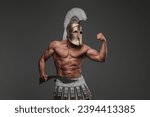 Portrait of an ancient Greek hoplite, posing in a studio with a bare muscular torso, wearing a helmet, and holding a gladius, set against a gray background