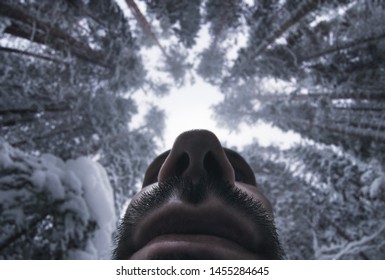 Portrait of an ancient man in the winter forest. View from the bottom.