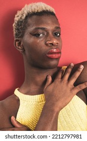 A Portrait Of An Androgynous Black Guy On A Red Background. Makeup Concept.