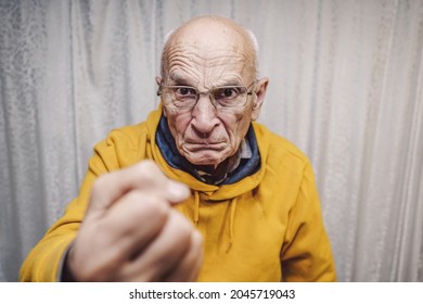 Portrait of angry caucasian man wearing eyeglasses and showing big fist standing at home indoor
