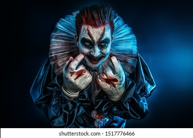 A portrait of an angry crazy clown from a horror film with a hammer. Halloween, carnival.