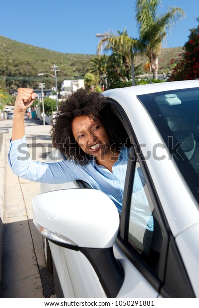 Portrait of angry female car driver showing her\
fist while driving
