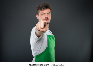 Portrait Of Angry Male Supermarket Employer Pointing Camera On Black Background With Copyspace Advertising Area