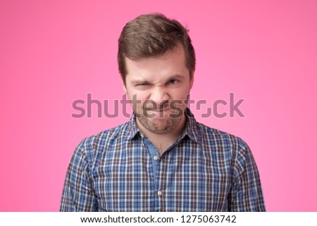 Portrait of an angry man on pink backfround. Negative facial emotion