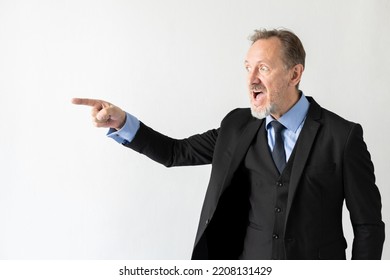 Portrait of angry mature businessman pointing at someone. Senior Caucasian manager wearing three piece suit looking away and shouting against white background. Angry boss concept - Shutterstock ID 2208131429