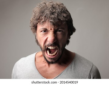 A Portrait Of An Angry Screaming Italian Man Wearing A T-shirt Against A Gray Background