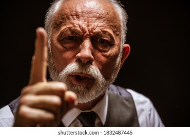 Portrait of angry senior man who threatens. Black background.