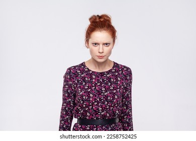 Portrait of angry unhappy young adult redhead woman wearing dress standing looking at camera, expressing aggression and hate. Indoor studio shot isolated on gray background. - Shutterstock ID 2258752425