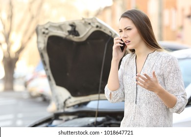 Portrait Of An Angry Woman Calling Insurance On Phone After Car Breakdown On The Street