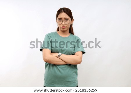 Portrait of angry young asian woman standing with arms folded on white background