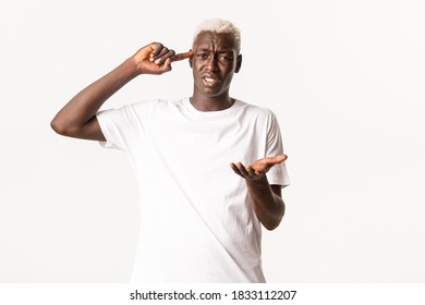 Portrait Of Annoyed African-american Blond Man, Complaining And Scolding Someone Acting Stupid, Pointing At Head, Standing White Background