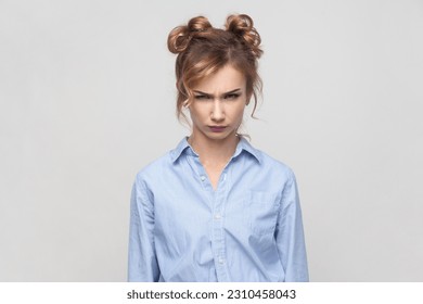 Portrait of annoyed irritated angry blonde woman feeling anxious and nervous, expressing fury and madness, wearing blue shirt. Indoor studio shot isolated on gray background. - Shutterstock ID 2310458043