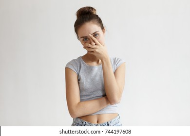 Portrait of annoyed stylish European girl wearing crop top with belly button showing, making face palm gesture, feeling bored while talking to her friend who speaking nonstop. Body language
