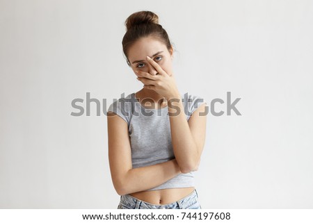 Portrait of annoyed stylish European girl wearing crop top with belly button showing, making face palm gesture, feeling bored while talking to her friend who speaking nonstop. Body language
