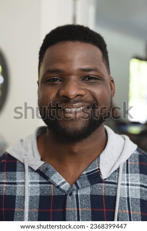 Portrait of appy african american man with beard standing and smiling in sunny house. Lifestyle,relaxation,free time and domestic life, unaltered.