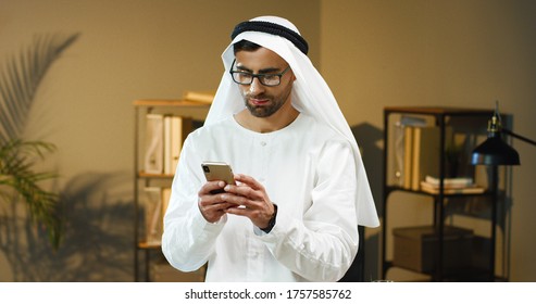 Portrait Of Arab Man In Glasses Using Mobile Phone In Office. 