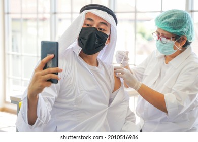 Portrait Of Arab Muslim Man Selfie By Phone At After Getting Covid Vaccine To Get Immunity. Nurse Use Hand Cover Plaster Arm In Clinic Or Hospital. People Wearing Protective Mask.