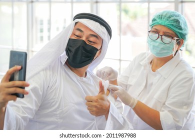 Portrait Of Arab Muslim Man Selfie By Phone At After Getting Covid Vaccine To Get Immunity. Nurse Use Hand Cover Plaster Arm In Clinic Or Hospital. People Wearing Protective Mask.