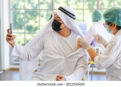 Portrait Of Arab Muslim Man Selfie By Phone At After Getting Covid Vaccine To Get Immunity. Nurse Use Hand Cover Plaster Arm In Clinic Or Hospital. People Wearing Protective Mask.