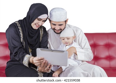 Portrait Of Arabian Family Sitting On The Sofa While Browsing Internet With A Digital Tablet