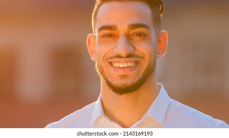 Portrait arabic Hispanic man businessman ethnic bearded guy wears formal shirt stands posing outdoors in street in sun sunset looking at camera smiling toothy dental waving head yes nods positively - Shutterstock ID 2143169193