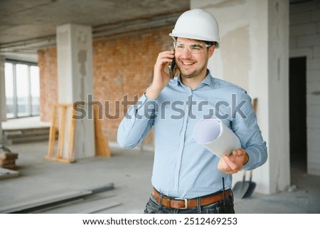 Portrait of an architect builder studying layout plan of the rooms, civil engineer working with documents on construction site, building and home renovation, professional foreman at work
