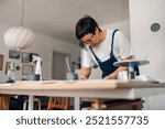 Portrait of artistic craftswoman in overalls standing at creative ceramics workshop and working with wet clay. Focused female creative pottery designer making earthenware at pottery studio. Copy space