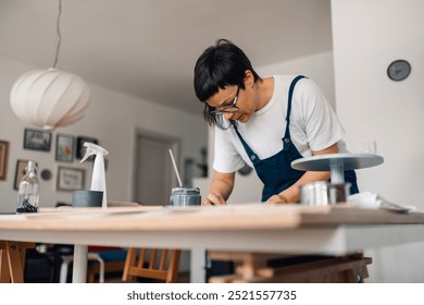 Portrait of artistic craftswoman in overalls standing at creative ceramics workshop and working with wet clay. Focused female creative pottery designer making earthenware at pottery studio. Copy space - Powered by Shutterstock