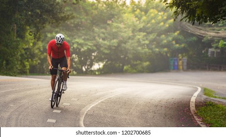 Portrait of Asia cyclist in red cycling jersey. A moment of a man who ride a bicycle up high on hill. Concept for morning ride, healthy hobby. - Shutterstock ID 1202700685