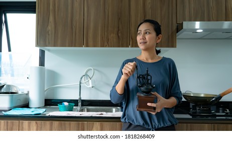 Portrait Of Asia Woman Holding Coffee Grinding Machine In The Kitchen