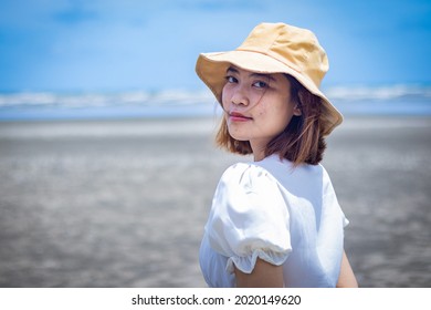 Portrait Of Asia Woman Relax And Happy With Yellow Bucket Hat On The Beach
