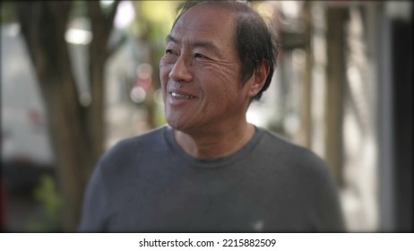 Portrait Of An Asian American Middle Aged Man Walking City Street Sidewalk In Blurred Shot. Happy Carefree Person Walks Outdoors In Urban Sidewalk