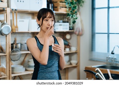 Portrait Of An Asian Athletic Girl Is Enjoying Yogurt In The Morning After Workout At A Bright Cozy Home Kitchen Interior.