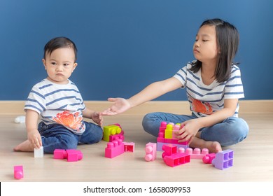 Portrait of asian baby boy and older sister quarrel about toys.concept kids sharing.