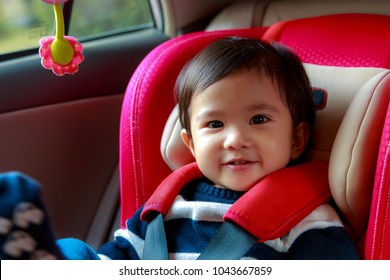 Portrait of Asian baby girl was smiling happily and sit in the red car seat for safety.while parents are going to travel