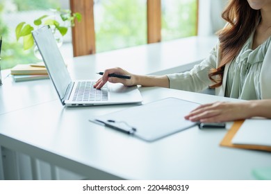 Portrait Of An Asian Bank Employee Using A Computer And Documents To Manage Financial Statements.