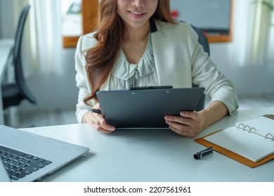 Portrait Of An Asian Bank Employee Using A Computer And Documents To Manage Financial Statements.