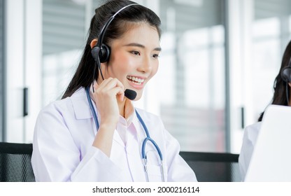 Portrait Asian Beautiful Female Doctor Smiling With Headsets, Sitting And Looking At Computer Screen, Making Online Telemedicine, Giving Service, Advise Medicines Or Medical Treatment To Patients