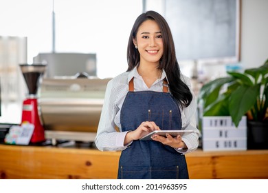 Portrait Of A Asian Beautiful Smiling Female Starting Small Business Owner With Tablet Near Counter In Her Cafe.