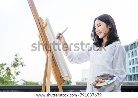 Portrait of asian beautiful woman paint in her art studio outdoor. Young asian girl holding her paintbrush. Artist workshop education concept